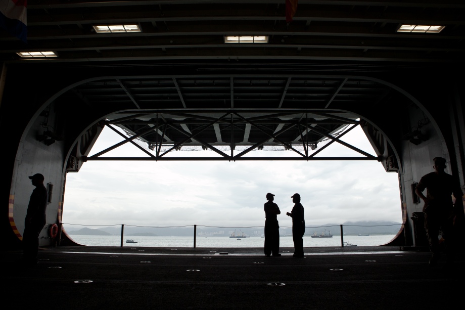 US Navy personnel on board the USS Makin Island speak below deck, in Hong Kong on August 20, 2014. Makin Island (LHD-8) a Wasp-class amphibious assault ship and the second ship of the US Navy to be named Makin Island, was laid down on February 14, 2004 by the Ingalls Shipbuilding, Pascagoula, Mississippi and was christened on 19 August 2006. AFP PHOTO / ANTHONY WALLACE